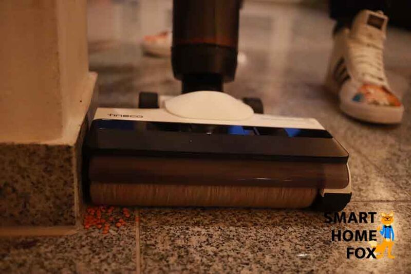 Man sieht, wie mit dem Tineco Floor One S5 Combo Dreck aus einer Kante entfernt wird.